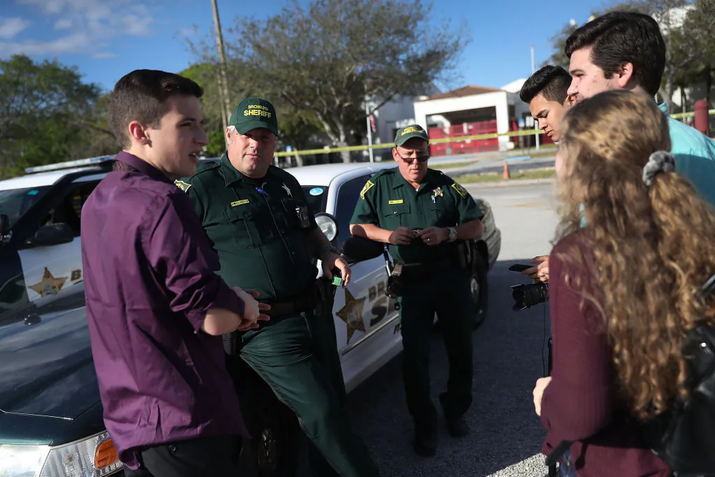 Cameron Kasky Jr. (L) and other students of Marjory Stoneman Douglas High School speak with Broward County Sheriff officers, Brad Griesinger and Jamie Rubenstein (L-R) who are guarding the front gate of the school on Feb. 18, 2018, in Parkland, Fla. Police arrested 19 year old former student Nikolas Cruz for the mass shooting that killed 17 people on Feb. 14, 2018. (Joe Raedle/Getty Images)