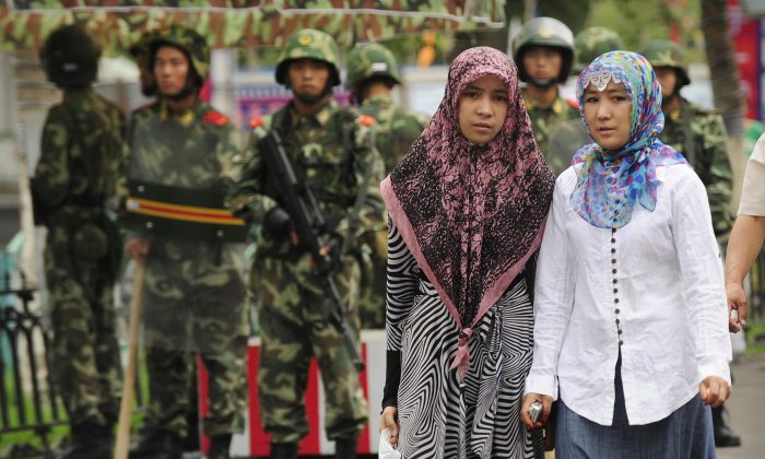 Two ethnic Uighur women pass Chinese paramilitary policemen standing guard outside the Grand Bazaar in Urumqi in China's Xinjiang region on July 14, 2009. (Peter Parks/AFP/Getty Images)