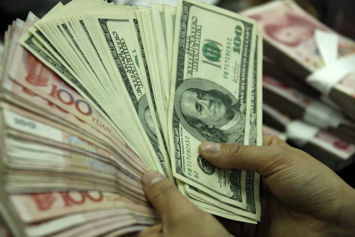 A clerk counts U.S. dollars and Chinese yuan in Hefei, east China's Anhui Province in this undated photo. (STR/AFP/Getty Images)