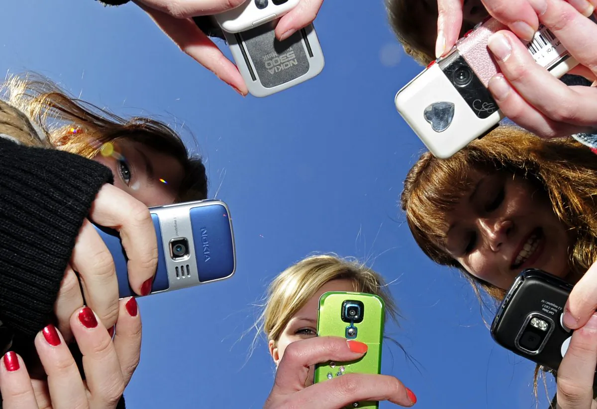 Teenagers use cell phones after school time on March 30, 2010. (OLIVIER MORIN/AFP/Getty Images)