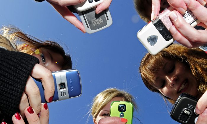 Teenagers use cell phones after school time on March 30, 2010. (OLIVIER MORIN/AFP/Getty Images)