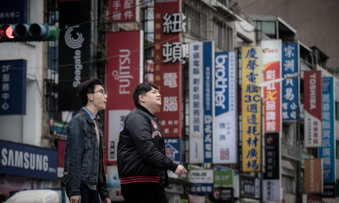 Pedestrians cross a street lined with the signs of electronic brands in Taipei on Jan. 12, 2016. (Philippe Lopez/AFP/Getty Images)