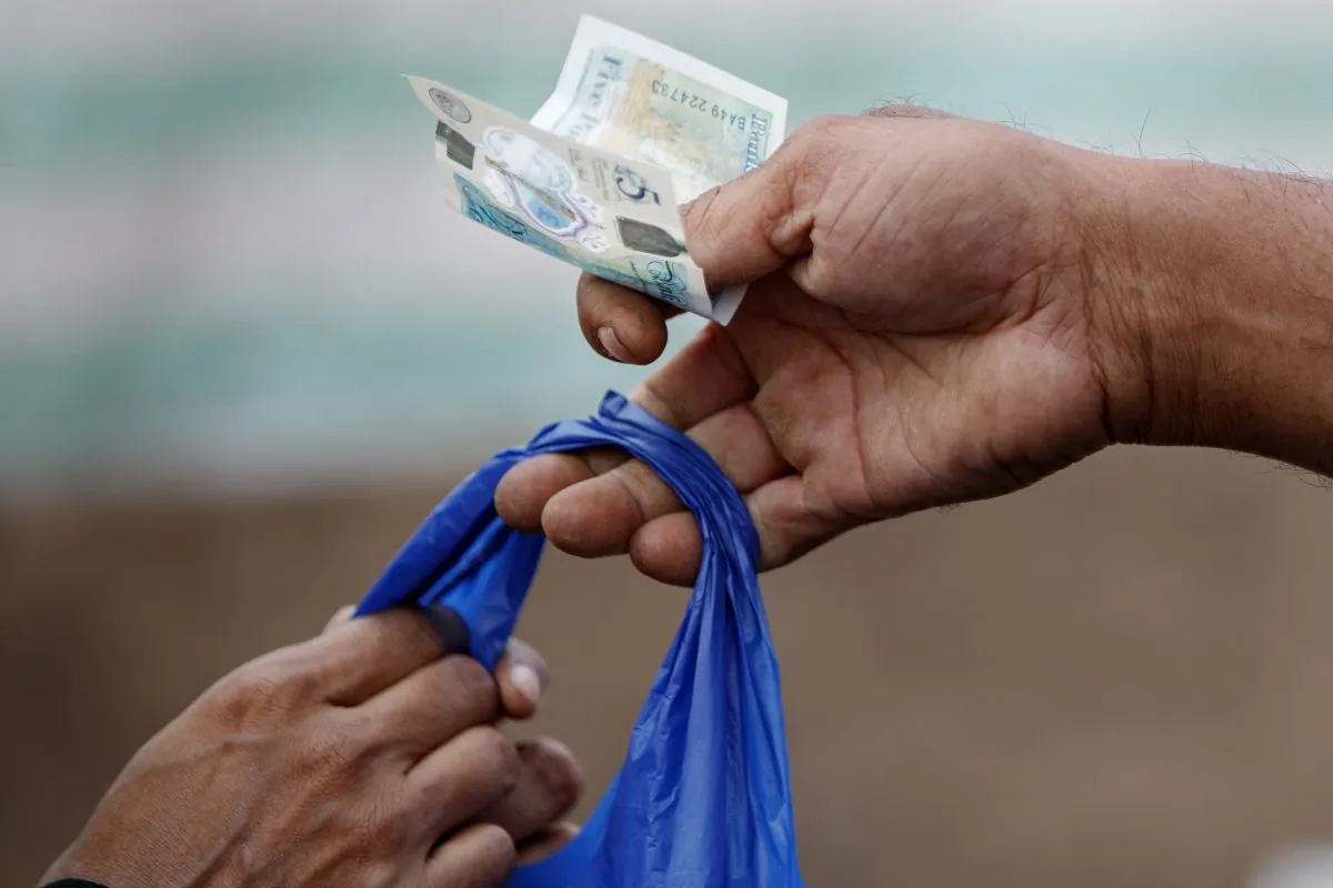 A customer uses a five-pound sterling note to pay a shopkeeper. Cash as a payment method isn’t going away anytime soon in advanced economies, according to new research from the Bank of International Settlements. (Tolga Akmen/AFP/Getty Images)