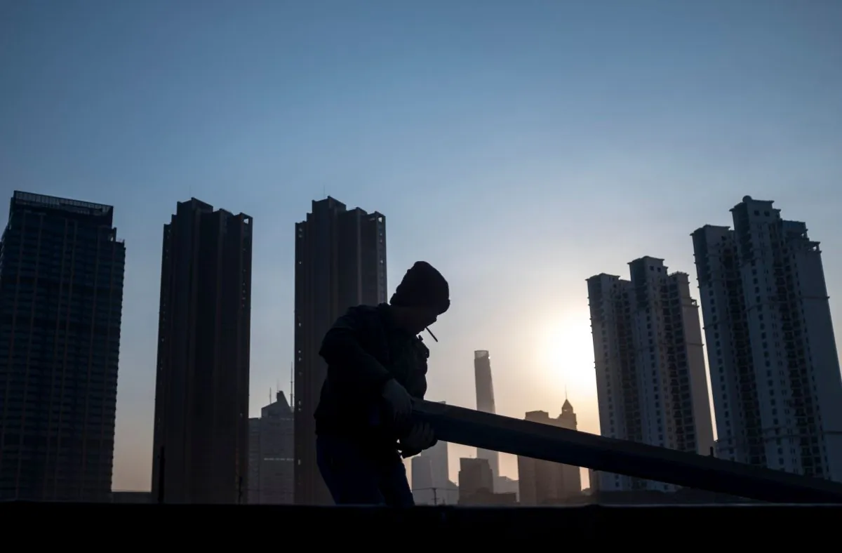 A man collects rubble on a construction site near the skyline of the Lujiazui Financial District in Shanghai, China on February 4, 2018. (Johannes Eisele/AFP/Getty Images)