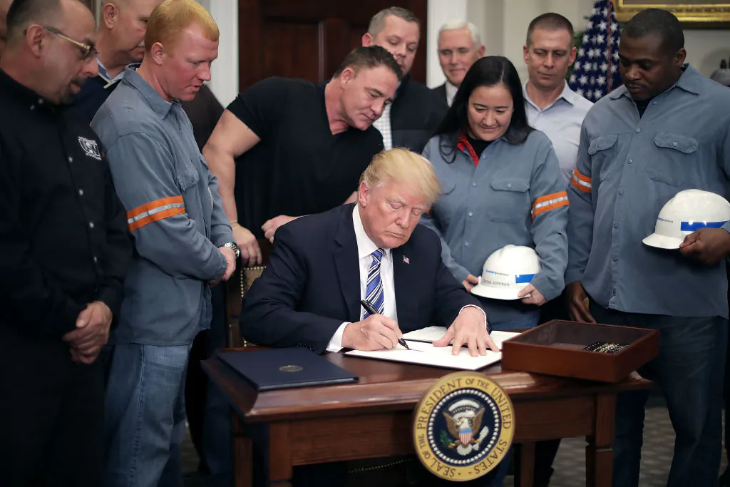 Surrounded by steel and aluminum workers, U.S. President Donald Trump signs a 'Section 232 Proclamation' on steel imports during a ceremony in Roosevelt Room at the White House in Washington, on March 8, 2018. (Chip Somodevilla/Getty Images)