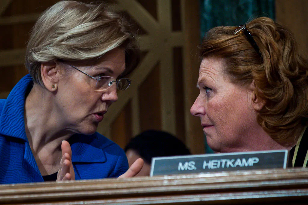 Senators Elizabeth Warren (D-Mass.) and Heidi Heitkamp (D-N.D.) confer during a Senate hearing in Washington on Jan. 30. Heitkamp accused Warren of exaggerating the danger posed by the changes to the Dodd-Frank Act. (Pete Marovich/Getty Images)