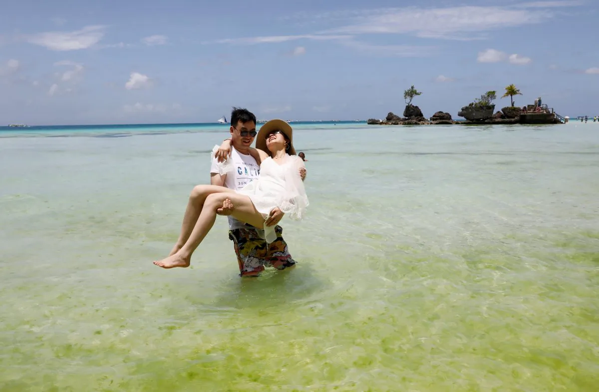 Newly-wed tourists frolic in the beach of Boracay in Philippines, April 8, 2018. (Reuters/Erik De Castro)