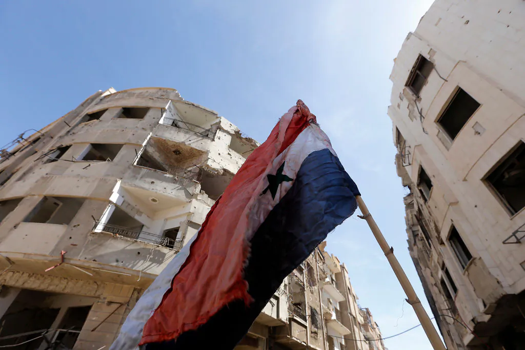 A general view shows a Syrian flag flying in a destroyed street in Jobar in Eastern Ghouta on April 2, 2018. (LOUAI BESHARA/AFP/Getty Images)