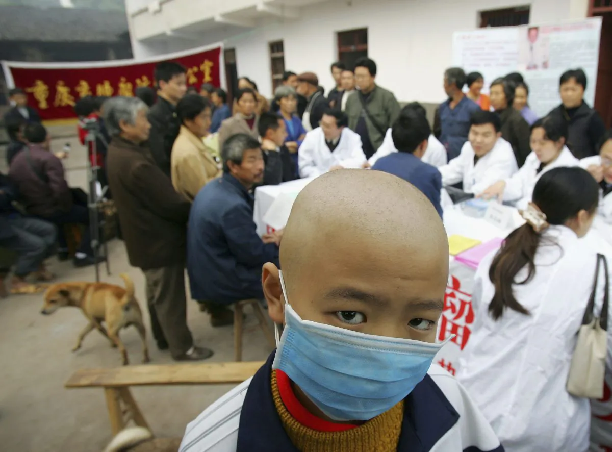 A Chinese boy diagnosed with leukemia wears a mask as he waits for a checkup by cancer specialists in the town of Longshi, in Chongqing City, China, on November 2, 2004. (China Photos/Getty Images)