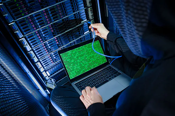 Symbolic photo with topic online crime, data theft and piracy: A man poses with a laptop showing a binary code in front of Server racks in a server center on January 12, 2018, in Berlin, Germany. (Thomas Trutschel/Photothek via Getty Images)