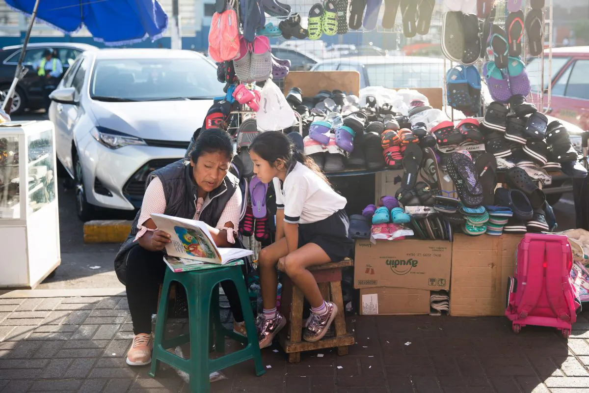 A woman reads with a child near the Mercado Surquillo No.1 in Lima, Peru, on Apr. 16, 2018. (Samira Bouaou/The Epoch Times)