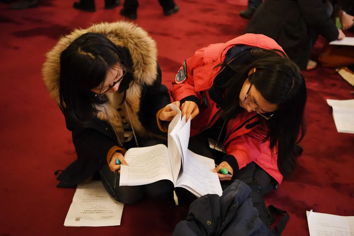 Chinese journalists pore over a copy of the government work report before the opening session of the National People's Congress, the Chinese regime’s rubber-stamp legislature, in Beijing on March 5, 2018. (Greg Baker/AFP/Getty Images)