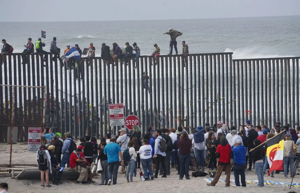 Migrant caravan demonstrators climb the U.S.-Mexico border fence during a rally in San Ysidro, California on April 29, 2018. (Sandy Huffaker/AFP/Getty Images)
