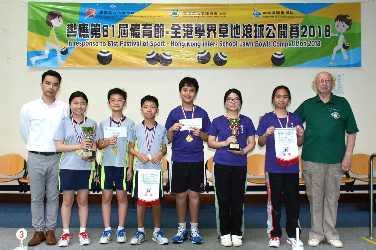 (L) Mr Law Hang Kong of the Hong Kong Leisure and Cultural Services Department, and (R) Mike Worth, Treasurer of HKLBA, presented the Inter-schools Lawn Bowls Competition awards to teams from Yan Oi Tong Tin Ka Ping Secondary School (in purple shirts) and Lutheran Tsang Shing Siu Leun School (in grey shirts). on Tuesday May 1, 2018. (Stephanie Worth).