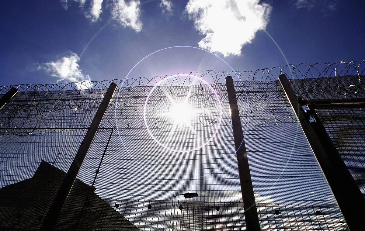 The sun shines through high security fencing surrounding Norwich prison in Norfolk, England, on Aug. 25, 2005. (Peter Macdiarmid/Getty Images)