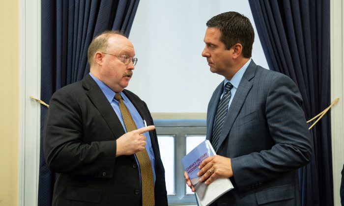 Richard D. Fisher Jr. (L), International Assessment and Strategy Center, gives a book titled "China's Military Modernization" to Rep. Devin Nunes (R-Calif.) after a Permanent Select Committee on Intelligence hearing on China’s Worldwide Military Expansion at the Rayburn House Office Building at U.S. Congress in Washington on May 17, 2018. (Samira Bouaou/The Epoch Times)