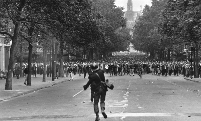 A policeman throws a tear gas canister to disperse crowds during student riots in Paris in the summer of 1968. The student protesters thought they would liberating people from consumer society, but ended up building a culture addicted to consumption  (Reg Lancaster/Getty Images)