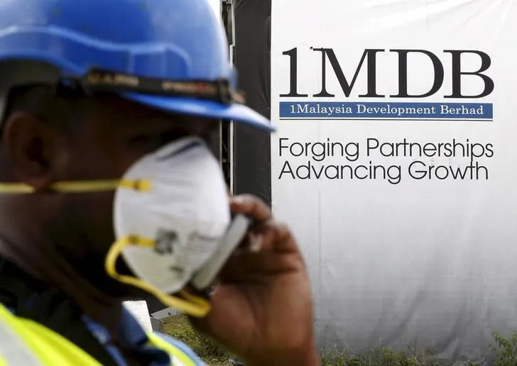 A construction worker talks on the phone in front of a 1Malaysia Development Berhad (1MDB) billboard at the Tun Razak Exchange development in Kuala Lumpur, Malaysia, in this Feb. 3, 2016 file photo. (Reuters/Olivia Harris/Files)