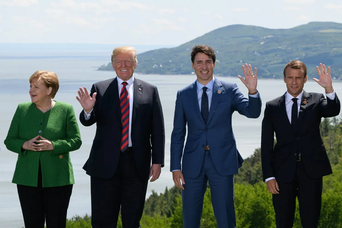 German Chancellor Angela Merkel, President Donald Trump, Canada's Prime Minister Justin Trudeau, and French President Emmanuel Macron wave during the family photo on the first day of the G7 Summit in La Malbaie, Canada, on June 8, 2018. (Leon Neal/Getty Images)