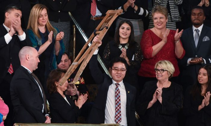 North Korean defector Ji Seong Ho raises his crutches as President Donald Trump delivers the State of the Union address in Washington, on Jan. 30, 2018. (SAUL LOEB/AFP/Getty Images)
