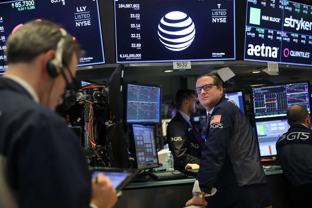 With a logo and trading information for AT&T behind them, traders and financial professionals work ahead of the closing bell on the floor of the New York Stock Exchange (NYSE) in New York City on June 13, 2018. (Drew Angerer/Getty Images)