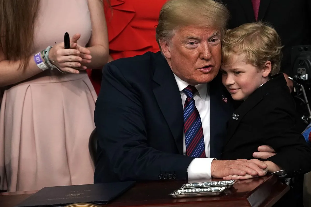 Duchenne Muscular Dystrophy (DMD) patient Jordan McLinn (R) of Indiana gives U.S. President Donald Trump (L) a hug during the signing ceremony for the Right to Try Act at the South Court Auditorium of the Eisenhower Executive Building May 30, 2018 in Washington, D.C. (Alex Wong/Getty Images)