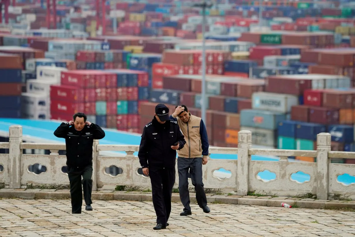 Security guards walk in front of containers at the Yangshan Deep Water Port in Shanghai, China, on April 24, 2018. (Aly Song/File Photo/Reuters)