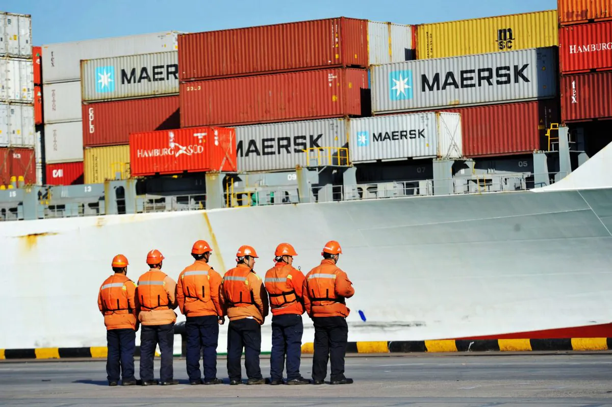 Workers stand in line next to a container ship in the Port of Qingdao, Shandong Province.(AFP/Getty Images)