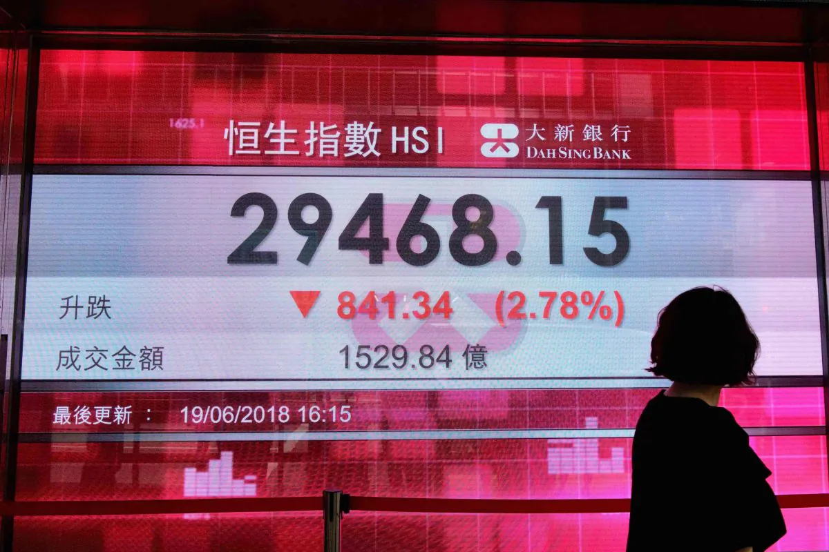 A pedestrian walks past a stocks display board after the Hang Seng Index closed at 29468.15, a loss of 2.78 percent, in Hong Kong on June 19, 2018. (Anthony Wallace/AFP/Getty Images)