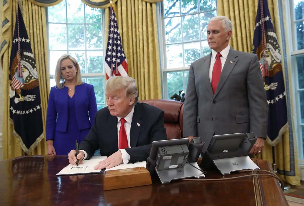 President Donald Trump, accompanied by Department of Homeland Security Secretary Kirstjen Nielsen (L) and Vice President Mike Pence (R), signs an executive order that will end the practice of separating family members who are apprehended after illegally entering the United States, in Washington on June 20, 2018. (Win McNamee/Getty Images)