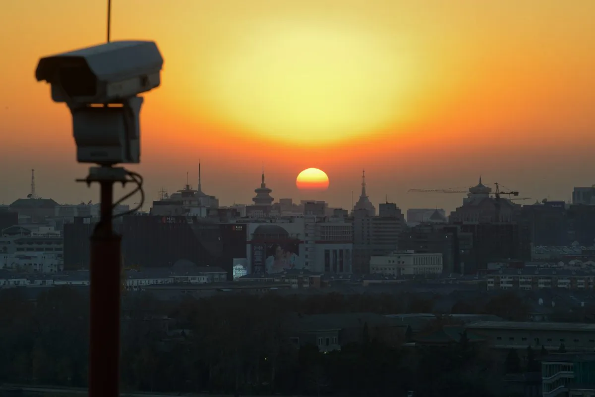 The sun sets behind the Beijing skyline and a security camera, on Dec. 5, 2013. (Ed Jones/AFP/Getty Images)