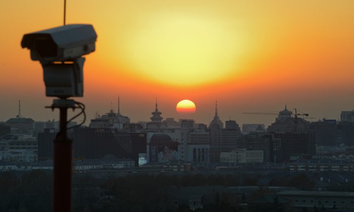 The sun sets behind the Beijing skyline and a security camera, on Dec. 5, 2013. (Ed Jones/AFP/Getty Images)