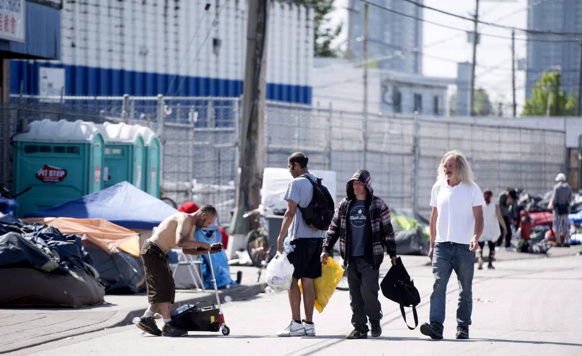 People walk past a tent city outside the Fraser Health supervised consumption site in Surrey, B.C., on June 6, 2017. (The Canadian Press/Jonathan Hayward)