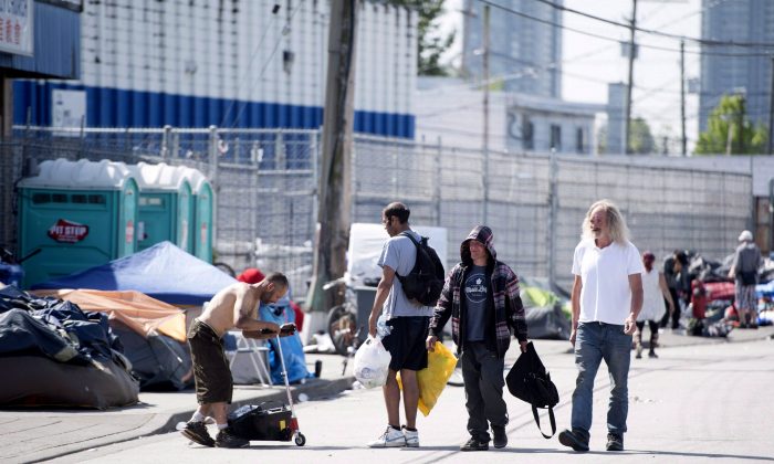 People walk past a tent city outside the Fraser Health supervised consumption site in Surrey, B.C., on June 6, 2017. (The Canadian Press/Jonathan Hayward)