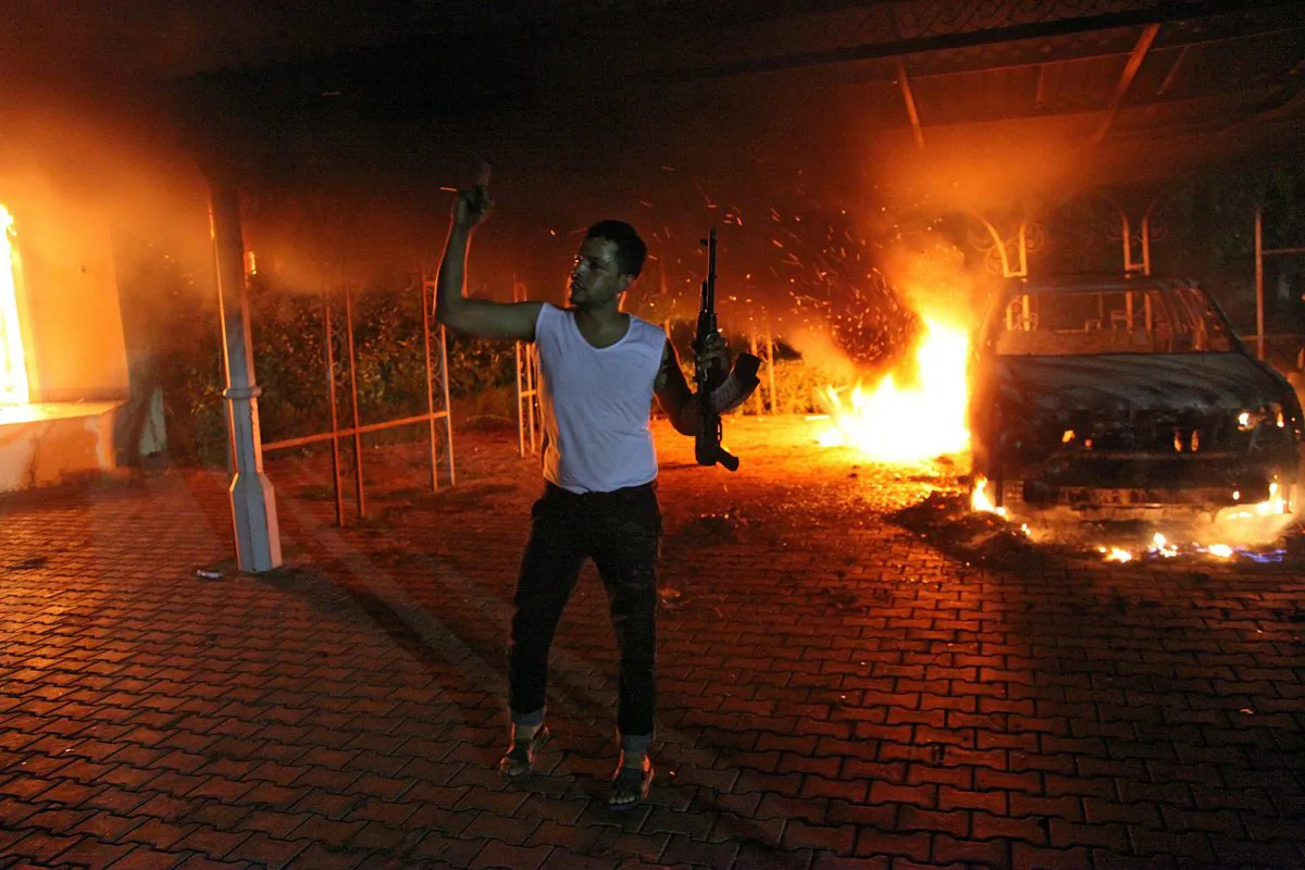 An armed man waves his rifle as buildings and cars are engulfed in flames after being set on fire inside the U.S. consulate compound in Benghazi on September 11, 2012. STR/AFP/GettyImages