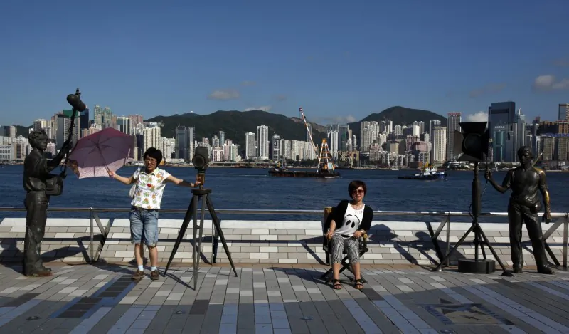 Mainland Chinese visitors pose beside bronze figures depicting the movie industry at the Avenue of Stars in Hong Kong on May 9, 2012. (Bobby Yip/Reuters)