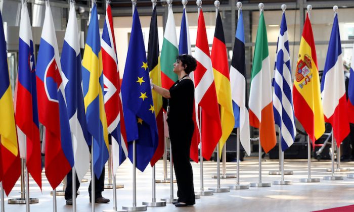 A woman adjusts flags ahead of European Union summit in Brussels, Belgium June 28, 2018.  (REUTERS/Yves Herman)