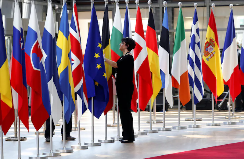A woman adjusts flags ahead of European Union summit in Brussels, Belgium June 28, 2018. (REUTERS/Yves Herman)
