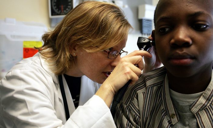 2006 年 4 月 11 日，在马萨诸塞州多切斯特的科德曼广场健康中心，一名医生在检查病人时通过耳镜观察。（Joe Raedle/Getty Images）