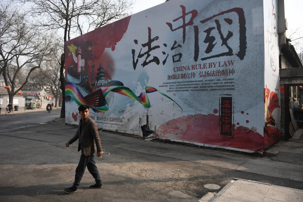 A security guard walks past a billboard with propaganda about rule of law in China on March 13, 2018. (Greg Baker/AFP/Getty Images)