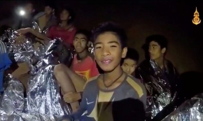 Boys from the under-16 soccer team trapped inside Tham Luang cave covered in hypothermia blankets react to the camera in Chiang Rai, Thailand, in this still image taken from a July 3, 2018 video by Thai Navy Seal. (Thai Navy Seal/Handout via Reuters TV)