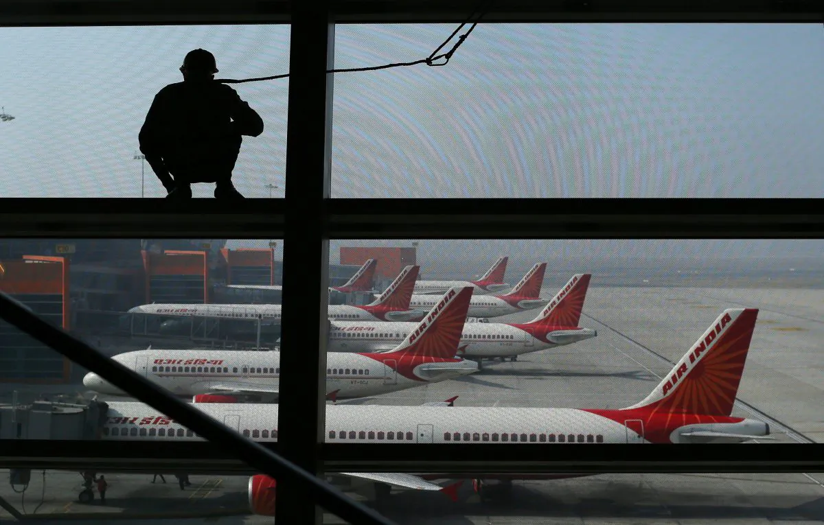 An Indian window cleaner stands on a beam overlooking Air India aircraft as they stand on the tarmac at Indira Gandhi International Airport in New Delhi on Nov. 17, 2012. (Andrew Caballero-Reynolds/AFP/Getty Images)