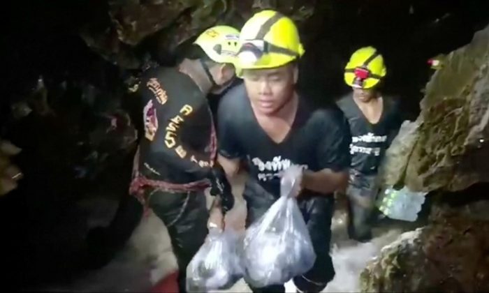 Rescuers carry supplies into the Tham Luang cave complex, where 12 boys and their soccer coach are trapped, in the northern province of Chiang Rai, Thailand, July 5, 2018. Video taken July 5, 2018. (RUAMKATANYU FOUNDATION/Handout via Reuters TV)