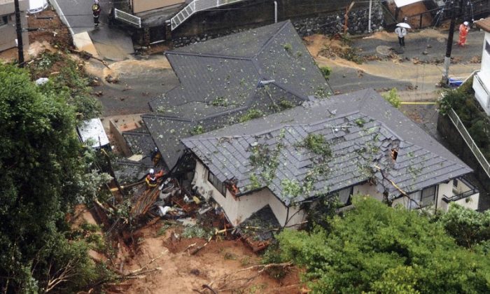 Rescue workers are seen next to houses damaged by a landslide following heavy rain in Kitakyushu, southwestern Japan, in this photo taken by Kyodo July 6, 2018. (Mandatory credit Kyodo/via REUTERS)