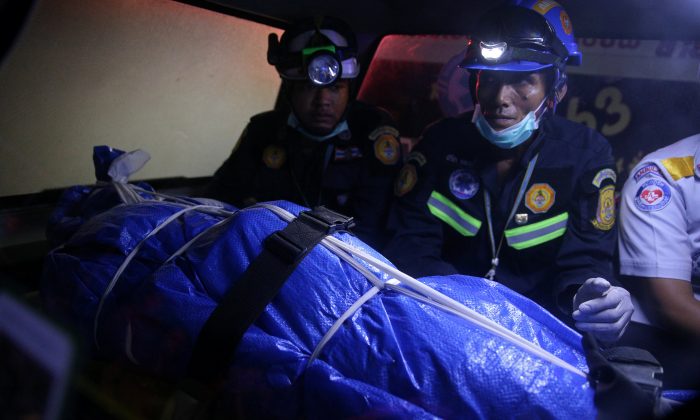 Thai Rescue workers sit next to the body of a victim on a stretcher, after a boat capsized off the tourist island of Phuket, Thailand, on July 7, 2018. (Reuters/Athit Perawongmetha)