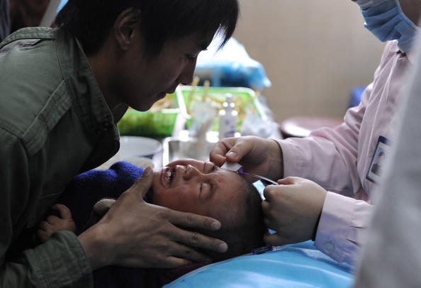 A Chinese man holds his son as a nurse administers an injection at a hospital in Hefei, a city in central China's Anhui Province on April 7, 2010. (STR/AFP/Getty Images)
