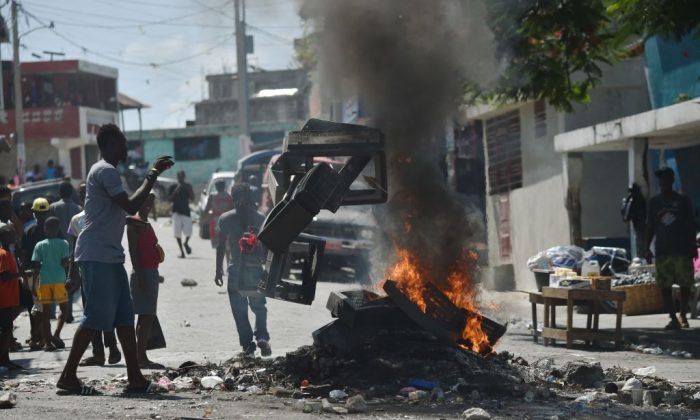 A demonstrator throws plastics onto a smoldering barricade in central Port-au-Prince, July 9, 2018, following two days of deadly looting and arson triggered by a quickly-aborted government attempt to raise fuel prices. (HECTOR RETAMAL/AFP/Getty Images)
