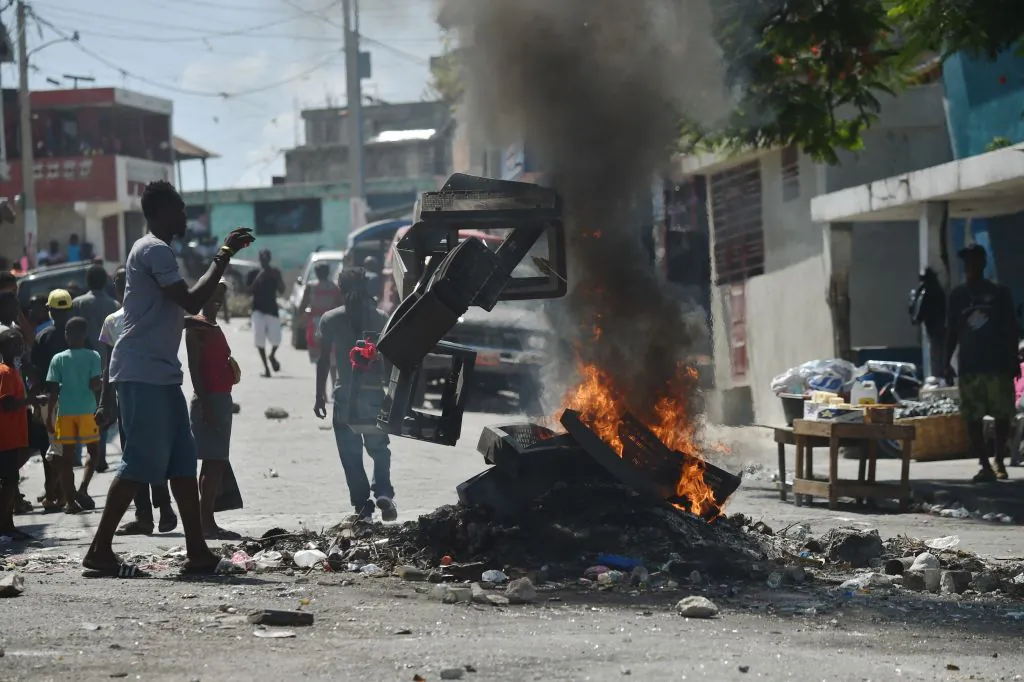 A demonstrator throws plastics onto a smoldering barricade in central Port-au-Prince, July 9, 2018, following two days of deadly looting and arson triggered by a quickly-aborted government attempt to raise fuel prices. (HECTOR RETAMAL/AFP/Getty Images)