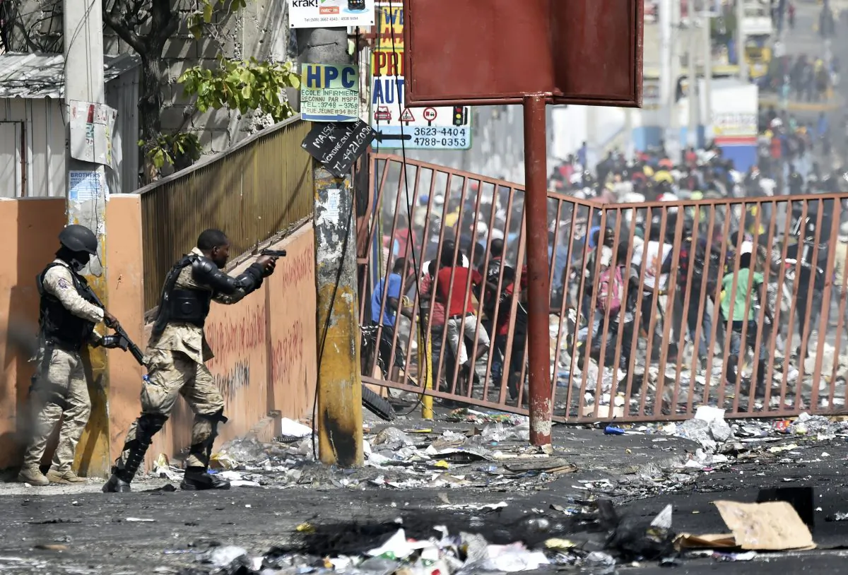 A member of the Haitian police points his gun at people to avoid looting in shops in Delmas, a commune near Port-au-Prince during protests against the rising price of fuel, on July 8, 2018. (Hector Retamal/AFP/Getty Images)
