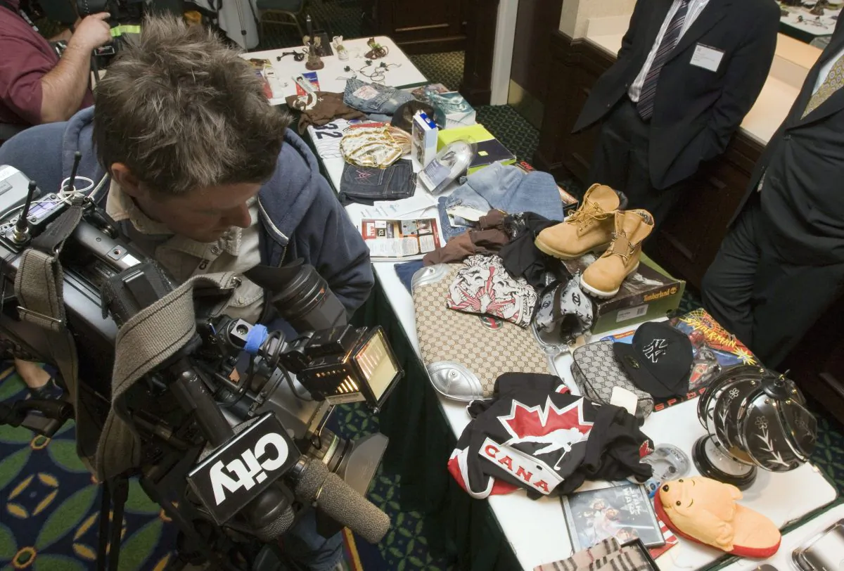 Television cameraman Jeff Ducharme shoots a display of counterfeit goods at a Canadian Anti-Counterfeiting Network conference in Toronto in this file photo. Anything can be counterfeit, from children's stuffed animals to electronics. (THE CANADIAN PRESS/Frank Gunn)